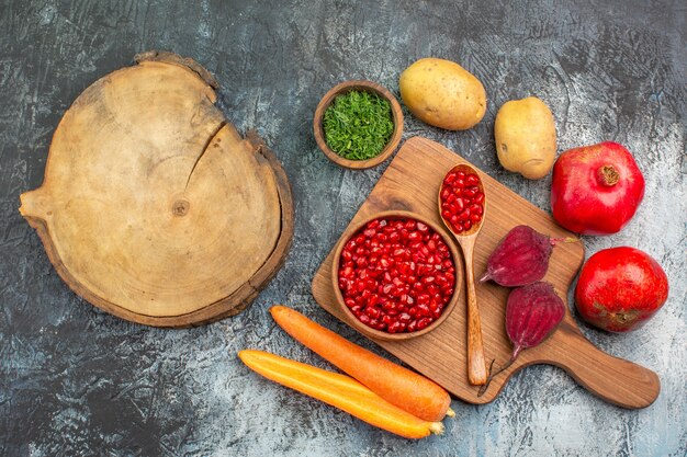 Top vue rapprochée légumes graines de grenade carottes betteraves pommes de terre herbes la planche à découper