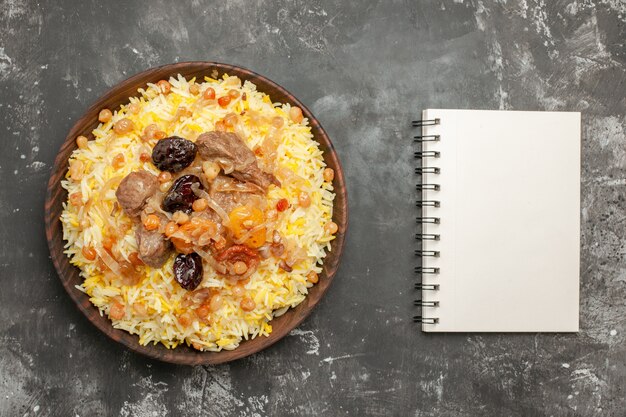 Top vue rapprochée pilaf pilaf avec de la viande fruits secs dans le cahier blanc bol brun