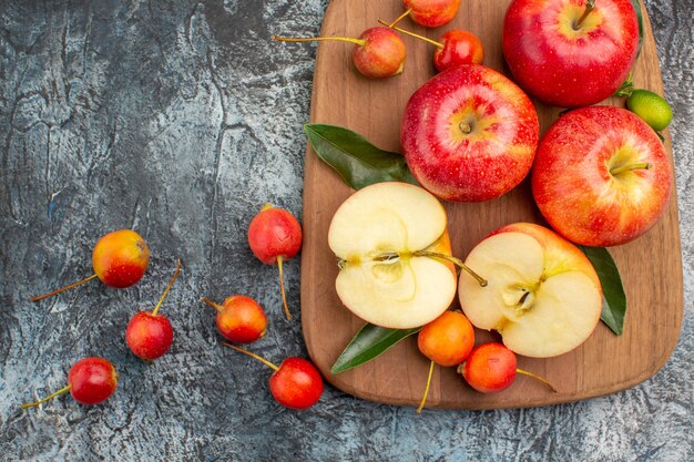 Top vue rapprochée pommes pommes rouges cerises sur la planche à découper