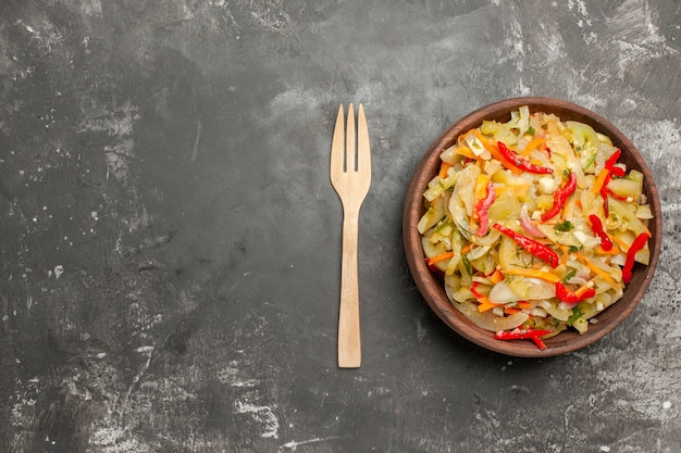 Top vue rapprochée salade une salade de légumes appétissante dans le bol fourchette en bois