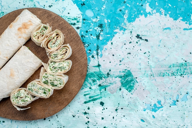 Photo gratuite top vue rapprochée de savoureux petits pains de légumes entiers et tranchés avec des verts sur bleu