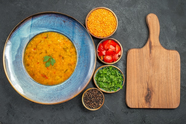 Photo gratuite top vue rapprochée soupe aux lentilles soupe aux lentilles tomates épices la planche à découper herbes