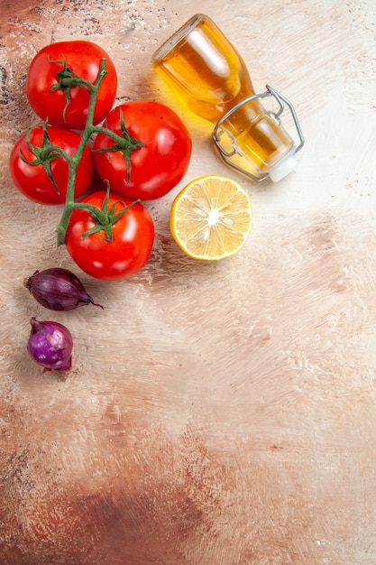Photo gratuite top vue rapprochée tomates tomates oignons citron bouteille d'huile sur la table