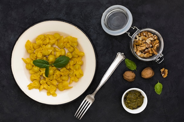 Photo gratuite tortellini cuits avec des feuilles de basilic et des ingrédients sur fond noir