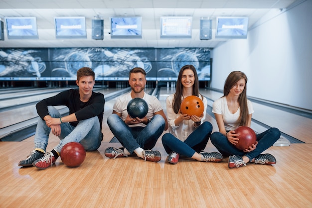 Toujours ensemble. De jeunes amis joyeux s'amusent au club de bowling le week-end