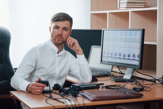 Photo gratuite toujours heureux de vous aider. l'examinateur polygraphique travaille dans le bureau avec l'équipement de son détecteur de mensonge