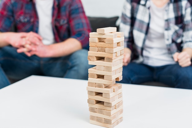 Tour de bloc en bois sur une table blanche devant un couple assis sur un canapé