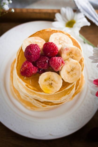 Photo gratuite tour de crêpes avec banane et framboises