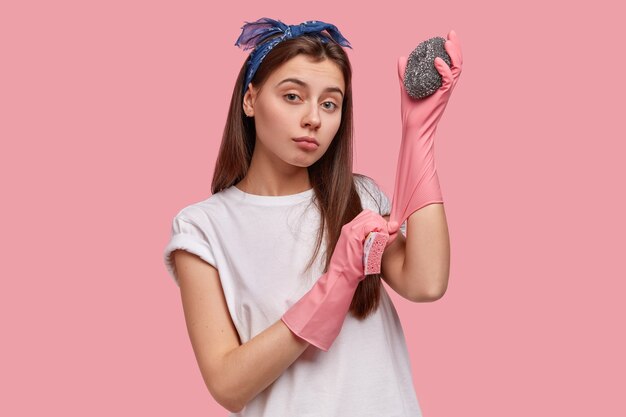 Tour de taille d'une jeune femme agréable à la recherche porte des gants de protection en caoutchouc, utilise deux éponges, nettoie l'hôtel