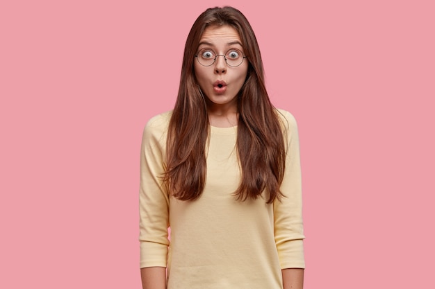 Tour de taille d'une jeune femme européenne brune émerveillée par des rumeurs choquantes, halète de choc, porte un pull jaune