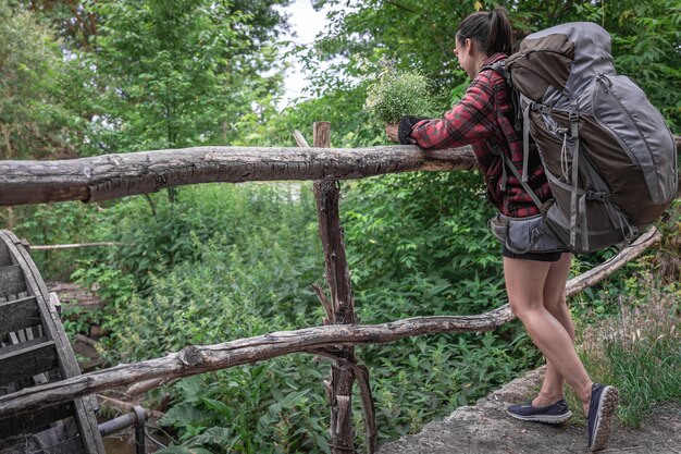 Touriste attirante de fille avec un grand sac à dos pour le voyage et avec un bouquet des fleurs sauvages.