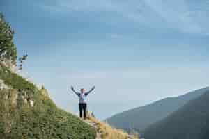 Photo gratuite un touriste aux mains levées se tient sur un col tout en escaladant les montagnes et en profitant du triomphe