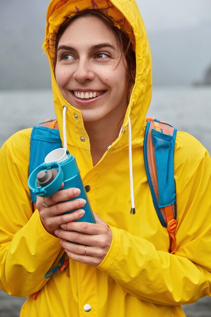 Le touriste insouciant et joyeux a une expression joyeuse, détourne le regard avec un large sourire