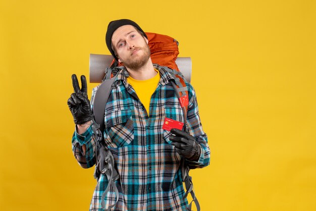 touriste mâle avec backpacker holding credit card faisant signe de victoire