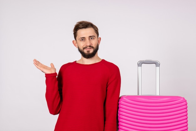 Touriste mâle vue de face avec sac rose sur mur blanc