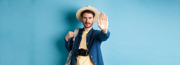 Photo gratuite un touriste masculin sérieux vous avertit de tendre la main pour montrer un geste d'arrêt homme en vacances interdire quelque chose