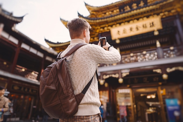 Touriste de sexe masculin prenant des photos d'une pagode au marché Yuyuan à Shanghai