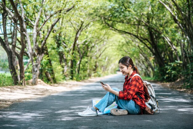 Les touristes assis et regardant les téléphones sur la route.