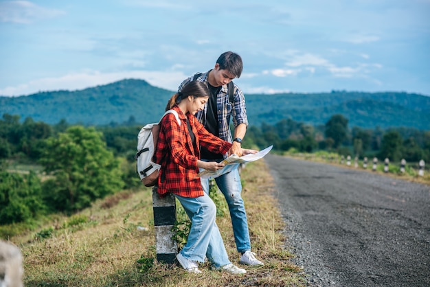 Les touristes masculins et féminins debout regardent la carte routière.