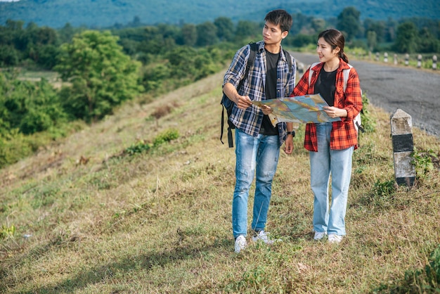 Les touristes masculins et féminins debout regardent la carte routière.