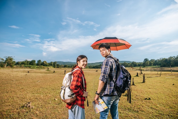 Les touristes masculins et féminins portent un sac à dos debout sur la pelouse.