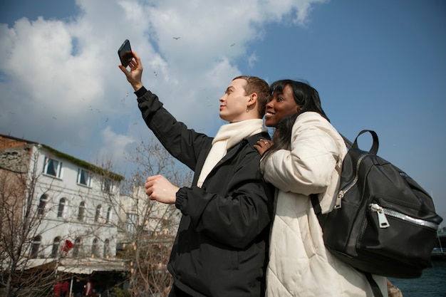 Touristes masculins et féminins prenant un selfie à l'extérieur avec leur smartphone