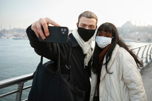 Touristes masculins et féminins prenant un selfie à l'extérieur avec leur smartphone