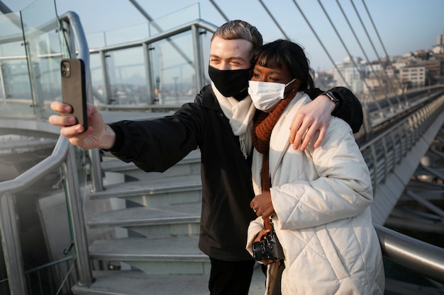 Touristes masculins et féminins prenant un selfie à l'extérieur avec leur smartphone