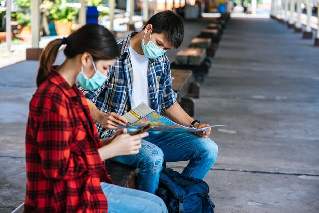 Les touristes masculins et féminins regardent la carte à côté de la voie ferrée.