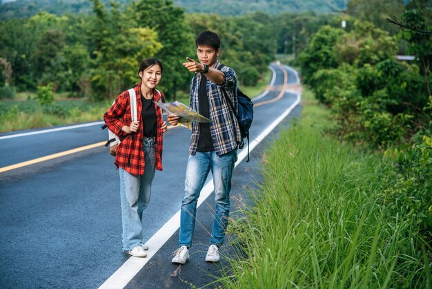 Les touristes masculins et féminins regardent la carte sur la route.