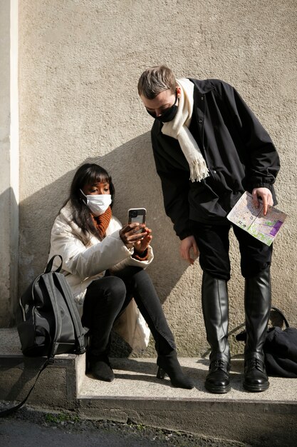 Touristes masculins et féminins vérifiant leur smartphone à l'extérieur