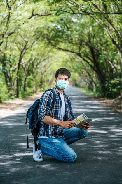 Les touristes masculins s'assoient et regardent la carte sur la route.