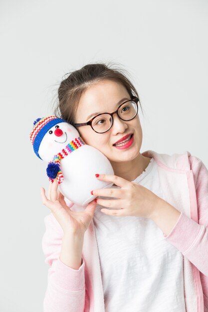 Tourné dans le studio de la jeune femme asiatique tenant un bonhomme de neige de Noël