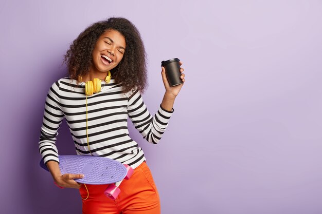 Tourné en studio isolé d'une femme patineuse heureuse posant avec une longue planche