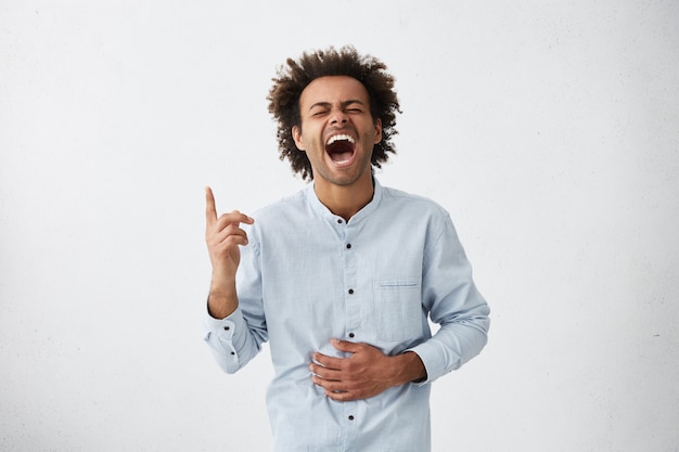 Tourné en studio isolé de jeune homme afro-américain joyeux positif avec des cheveux funky