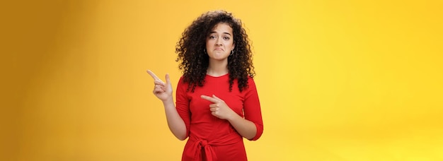 Photo gratuite tourné à la taille d'une fille contrariée et contrariée aux cheveux bouclés en bas dans les dépotoirs pointant vers le coin supérieur droit co