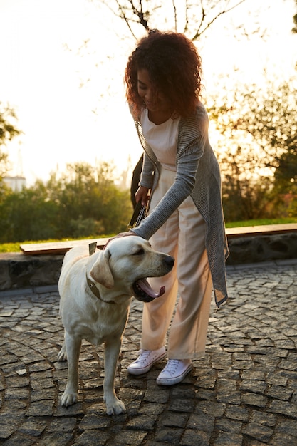 Tourné sur toute la longueur d'une jolie jeune femme en bonne santé marchant le matin dans le parc avec un chien