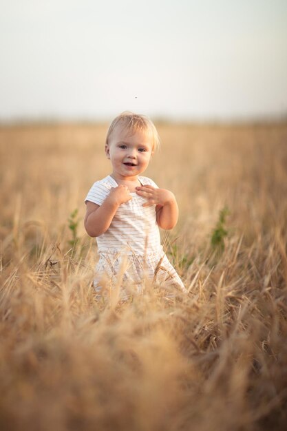 Tout-petit enfant sur le champ de blé au coucher du soleil