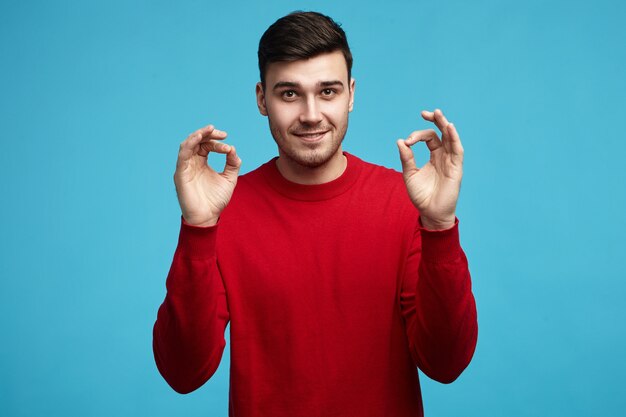 Tout va bien! Charismatique jeune homme aux cheveux noirs européen ayant une expression faciale confiante