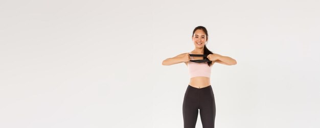 Toute la longueur d'une belle fille asiatique mince et en forme faisant des exercices de fitness étendant l'interdiction de résistance