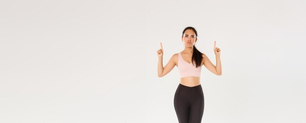 Toute la longueur de la fille de remise en forme réticente et déçue, une athlète féminine mince en vêtements de sport boudant et