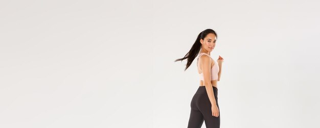 Toute la longueur de sassy goodlooking slim asian girl doing fitness femme athelte ou entraîneur d'entraînement walki