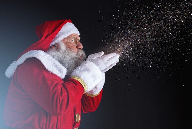 Traditions De Noël. Père Noël Soufflant Des Flocons De Neige. Photo Premium