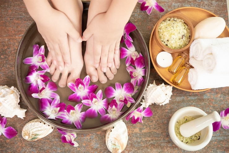 Photo gratuit traitement spa et produit pour pieds féminins et spa pour les mains. fleurs d'orchidées dans un bol en céramique.