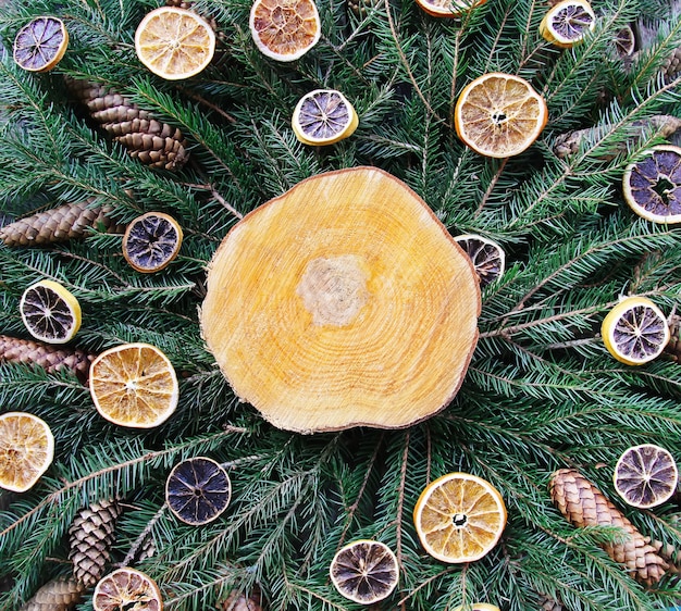 Tranche de bois sur des branches de sapin vert décorées de tranches d'orange séchées et de cônes. composition festive de vacances d'hiver vintage de noël et du nouvel an.