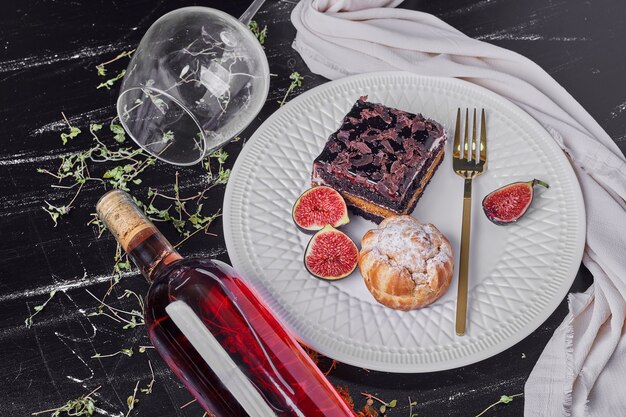 Une tranche carrée de gâteau au fromage au chocolat avec du vin.