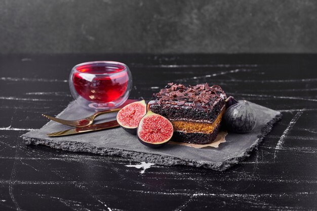 Une tranche carrée de gâteau au fromage au chocolat avec des figues et du vin.