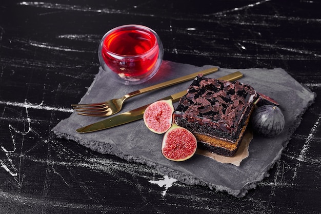 Une tranche carrée de gâteau au fromage au chocolat avec une tasse de vin.