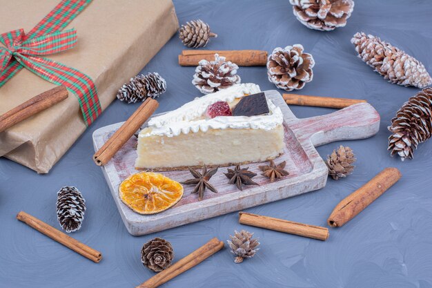 Une tranche de cheesecake dans un plateau en bois avec des fleurs d'anis et des bâtons de cannelle