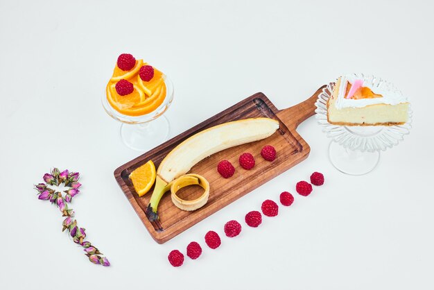 Une tranche de cheesecake avec un plateau de fruits de côté.